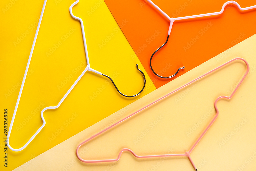 Clothes hangers on color background