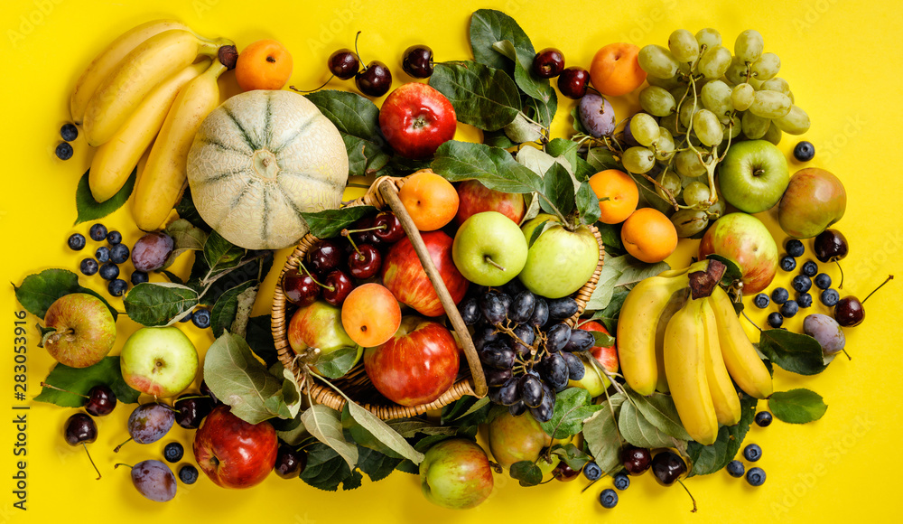 Flat-lay of fresh fruits and berries on yellow background