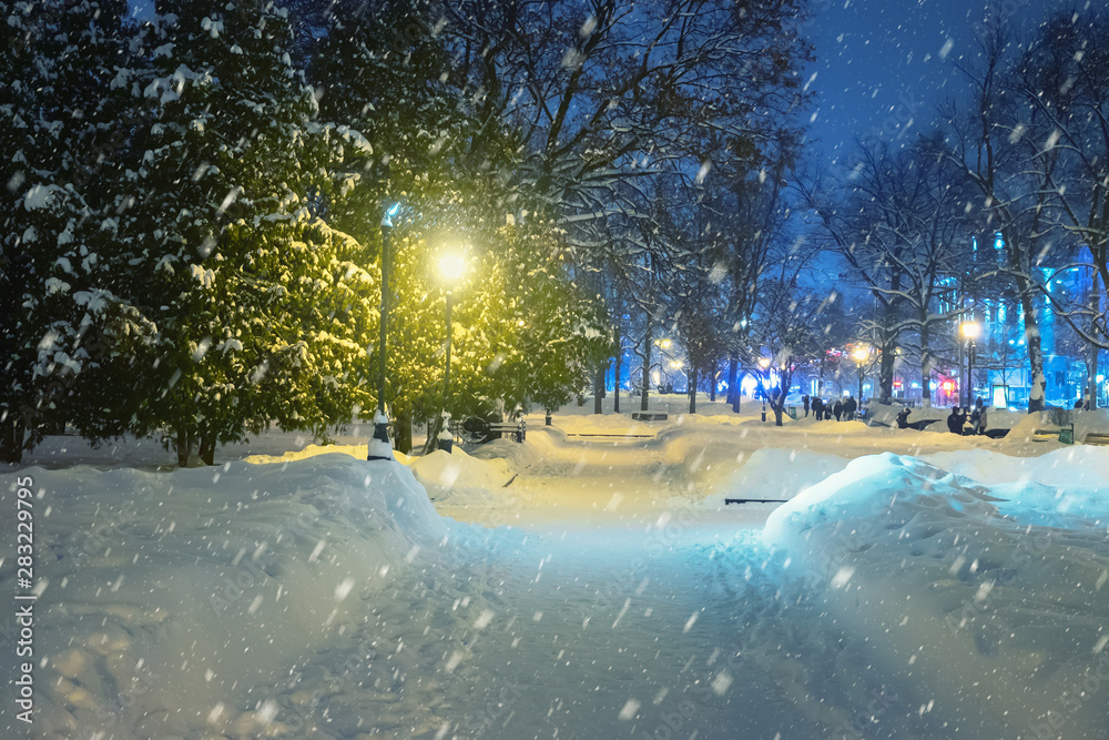 夜晚的冬季景观。城市街道上的雪花飘落，人们匆忙回家，霜冻天气。