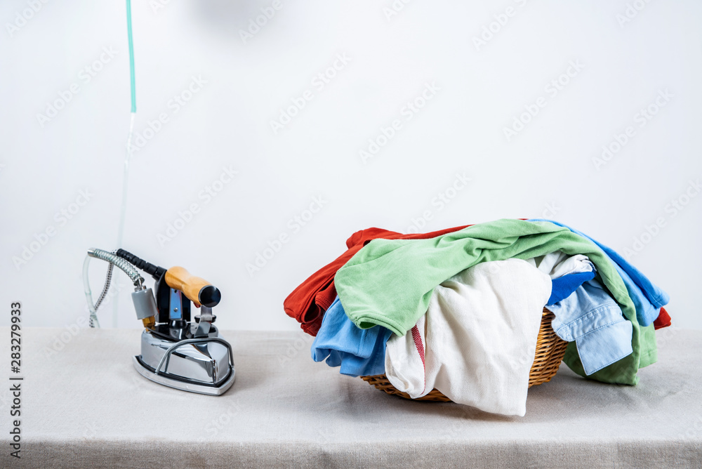 A pile of clothes and irons that need to be ironed on the table