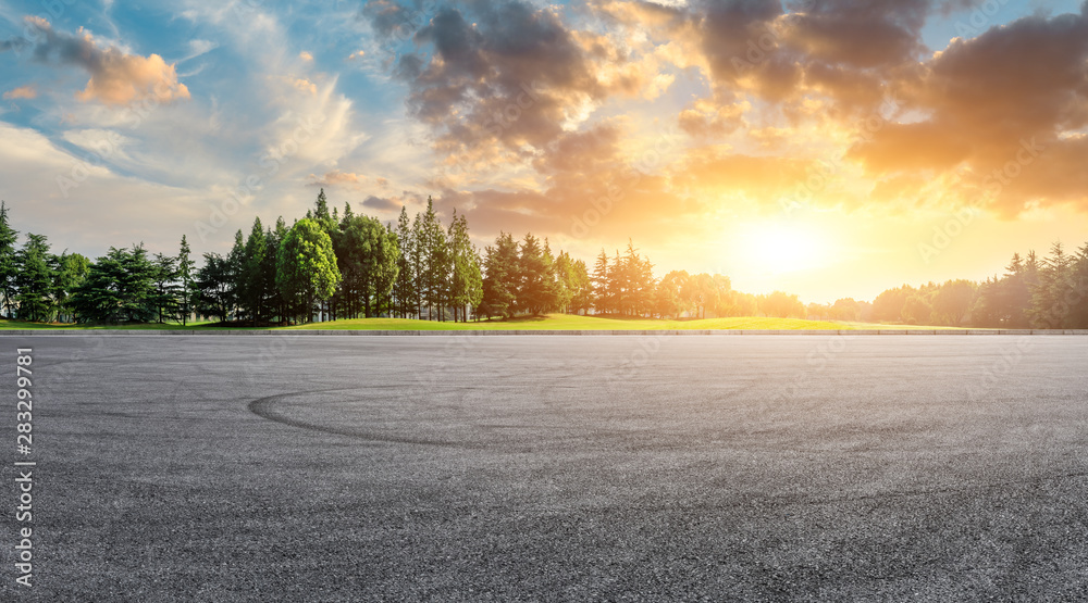 Asphalt race track and green woods nature landscape at sunset