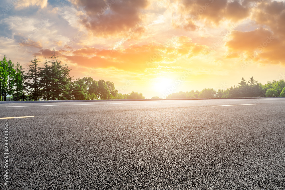 Country asphalt road and green woods nature landscape at sunset