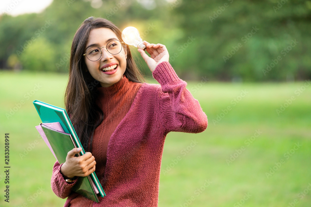 Creative young woman hold shinning light bulb. Concept of knowledge, intelligence and inspiration.