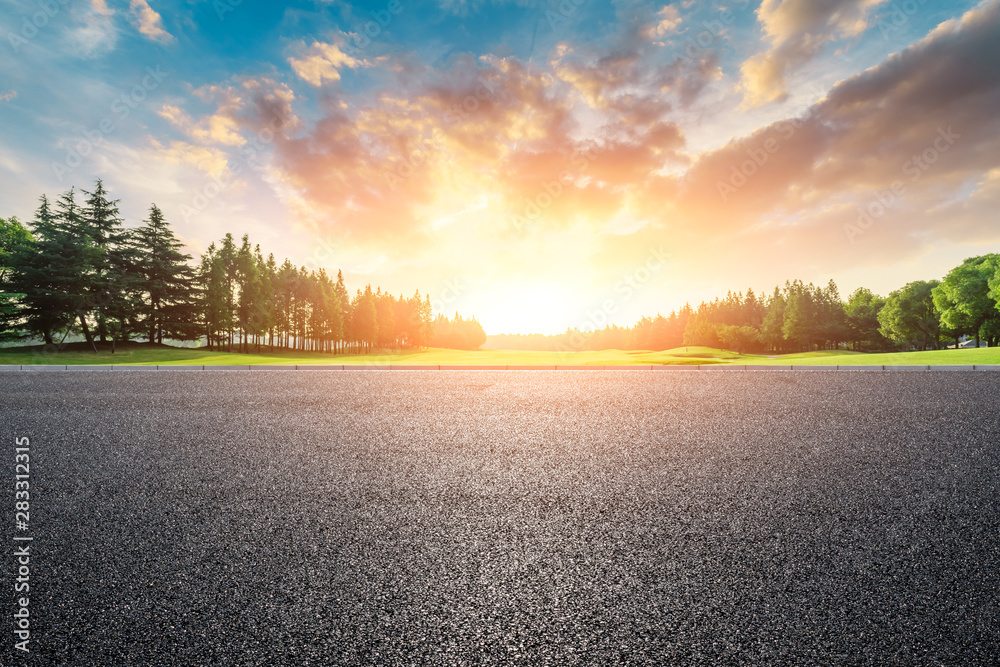 Country asphalt road and green woods nature landscape at sunset