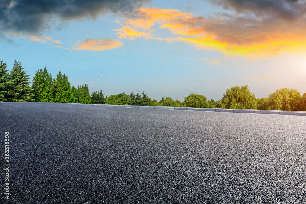 Country asphalt road and green woods nature landscape at sunset