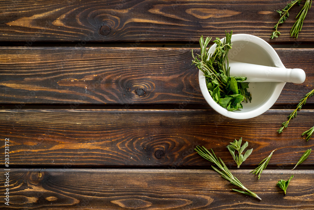 Homeopathy with leaves and healing herbs for making oil on wooden background top view copyspace