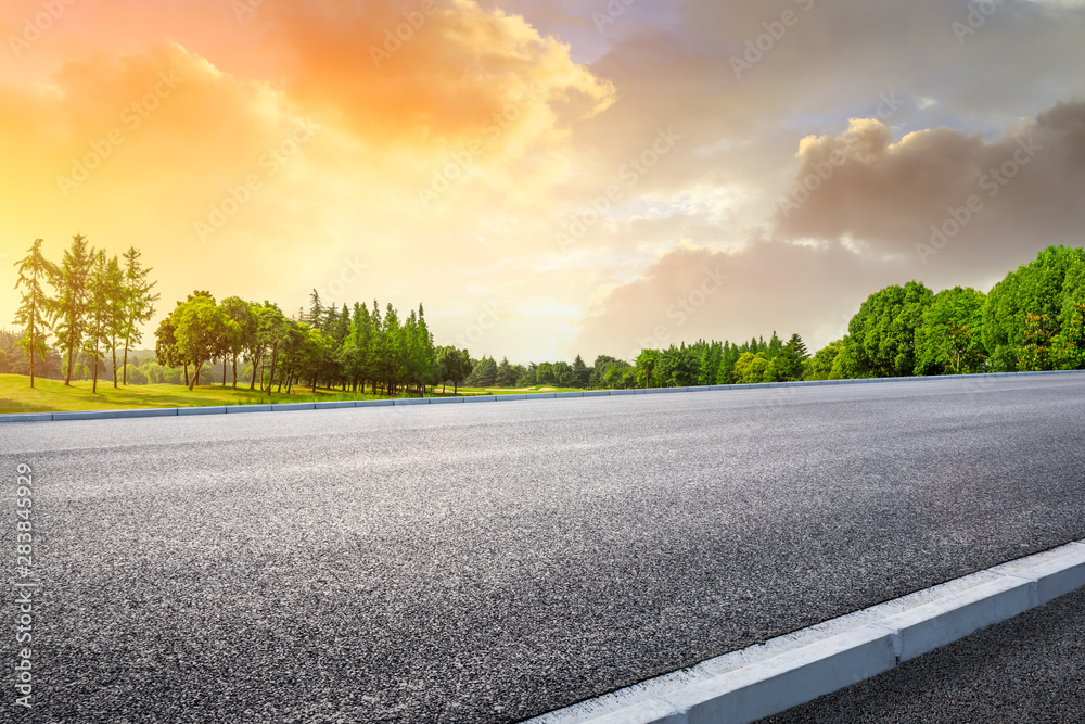 Country asphalt road and green woods nature landscape at sunset