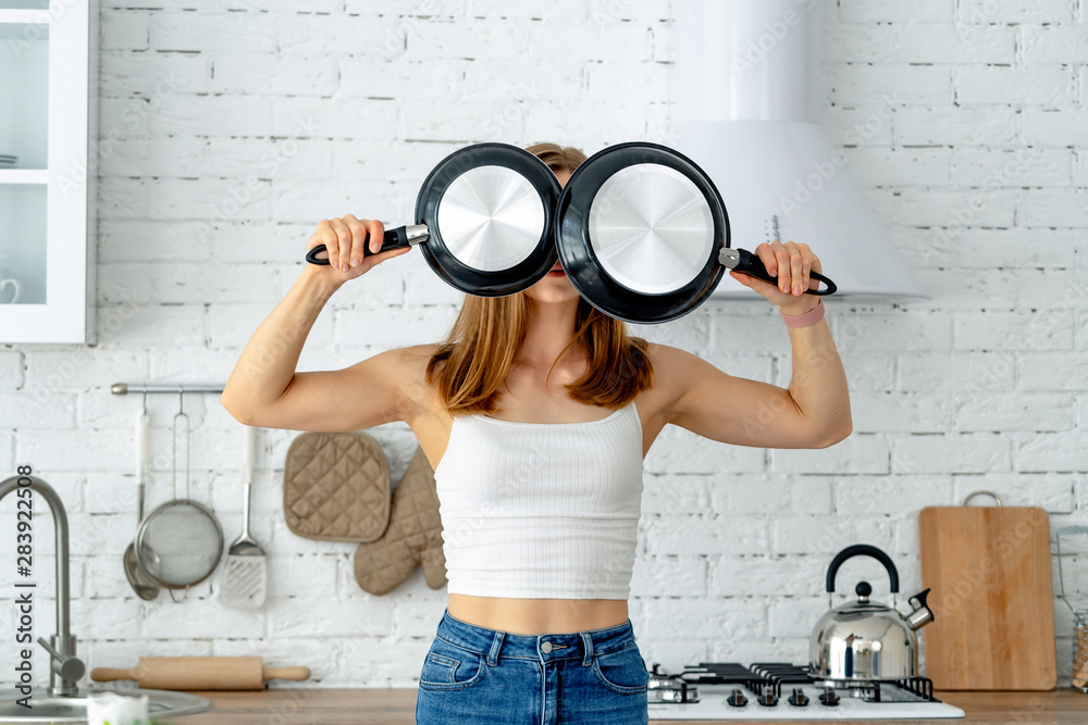 Portrait of funny housewife with kitchen utensils. Emotional expressive woman in kitchen