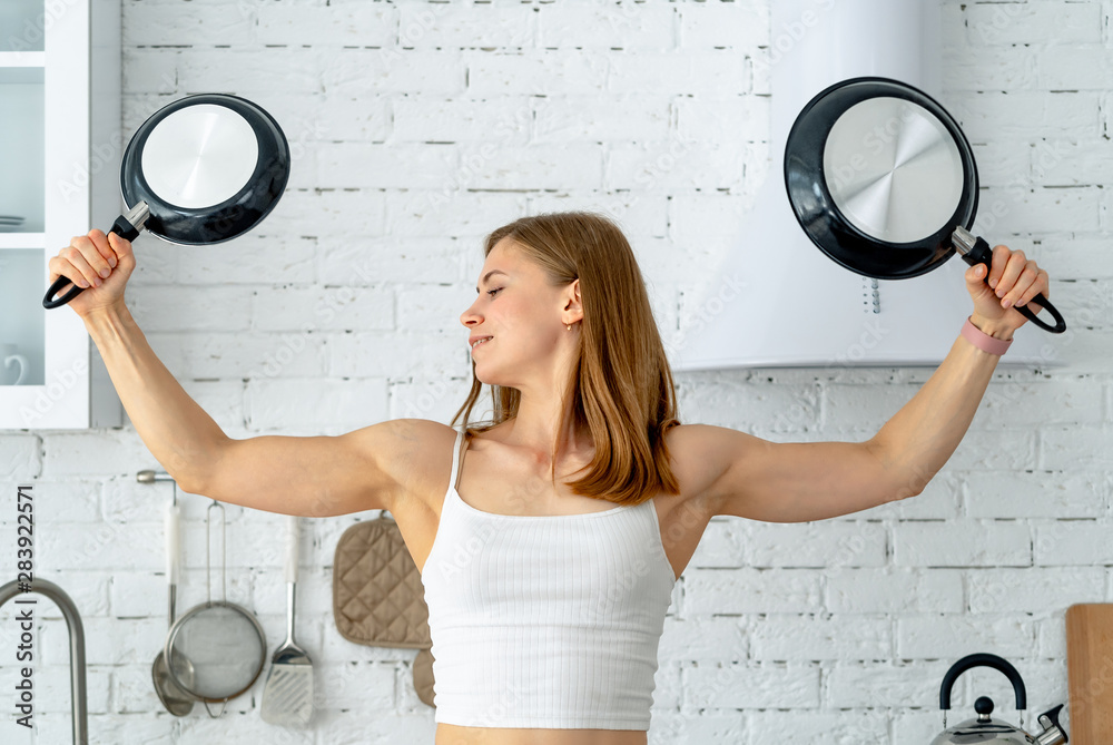 Strong woman holding frying pan. Housewife with kitchen utensils