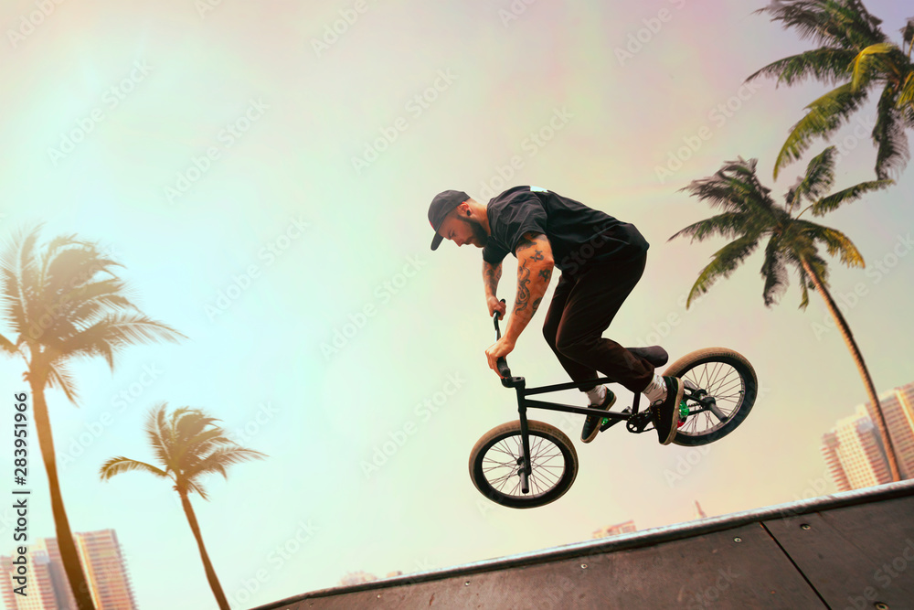 BMX rider is performing tricks in skatepark on sunset.