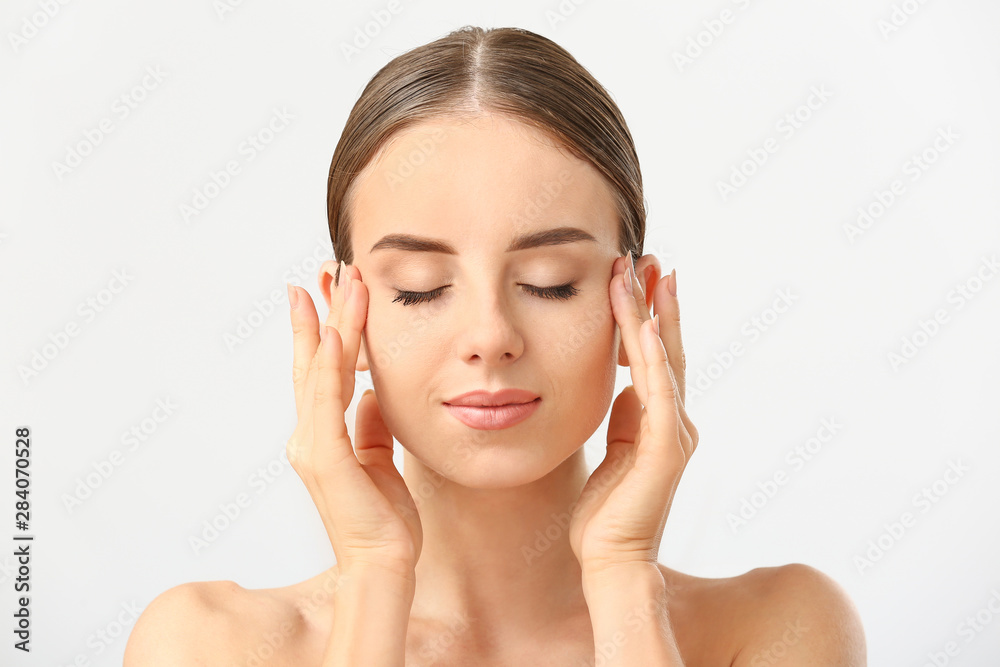 Beautiful woman massaging her face against white background