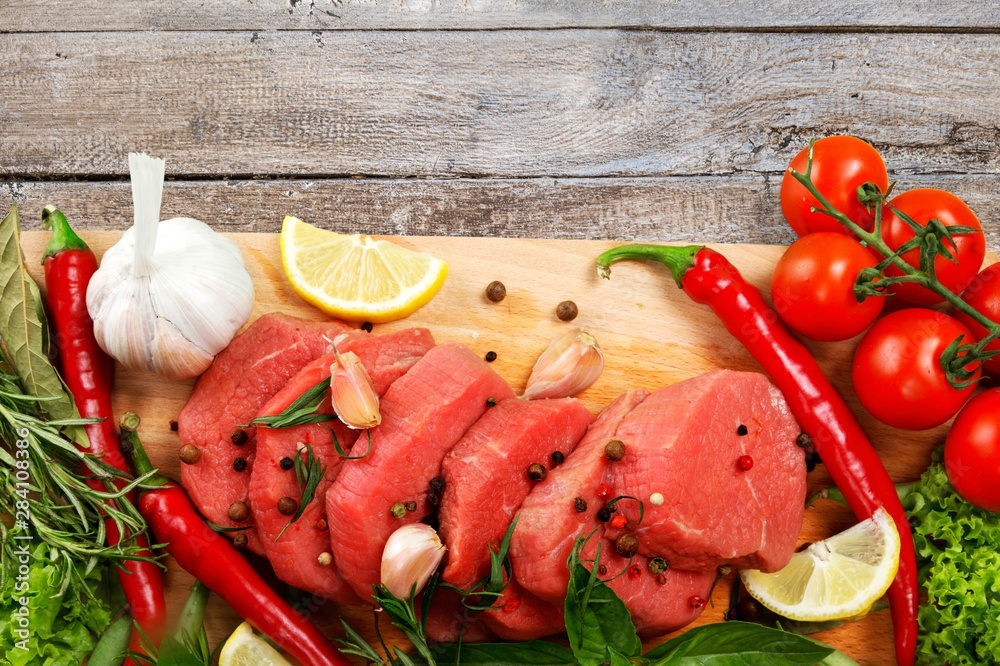 Fresh raw meat with vegetables on brown wooden table at wooden background