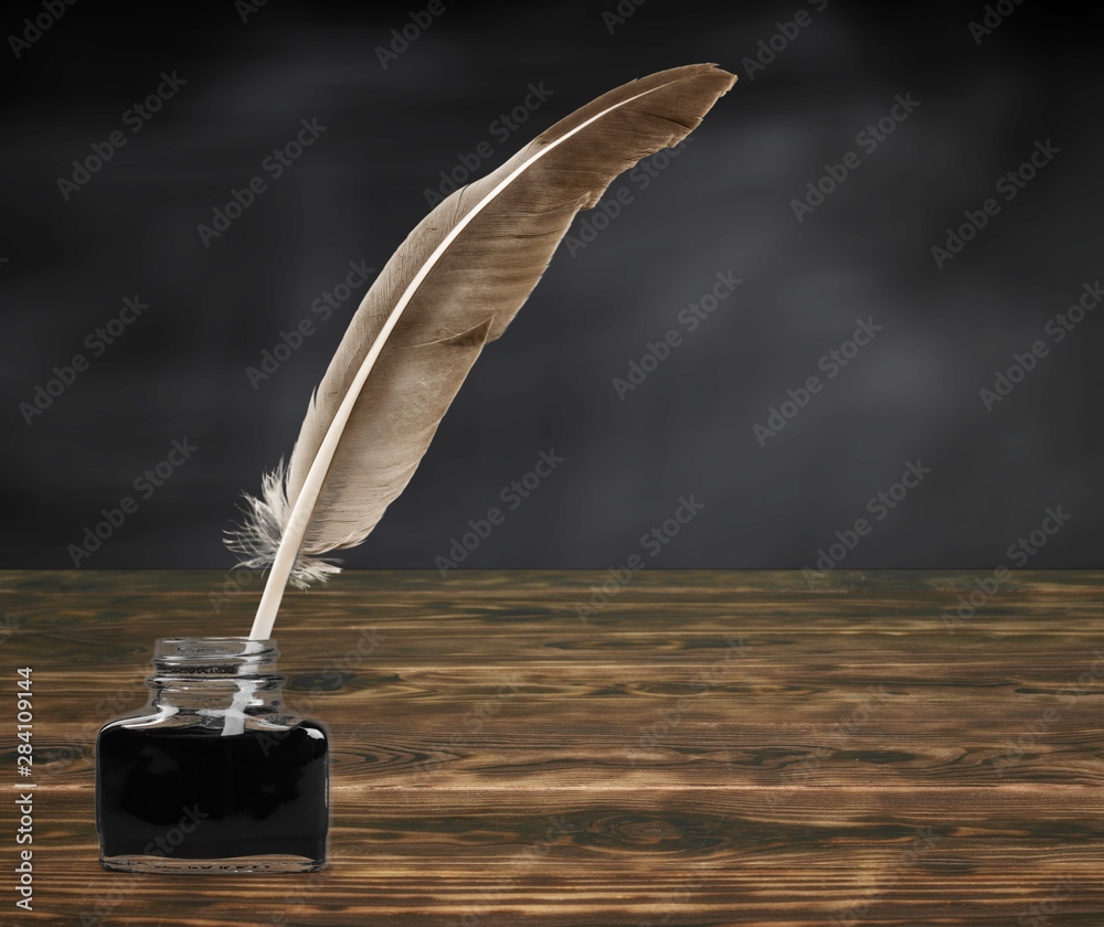 Feather quill pen and glass inkwell isolated on a white background