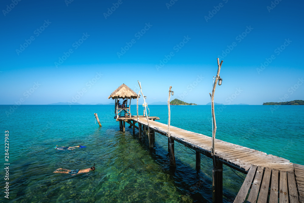 Tourists snorkel in crystal turquoise water near tropical resort at Koh Mak island in Trat, Thailand