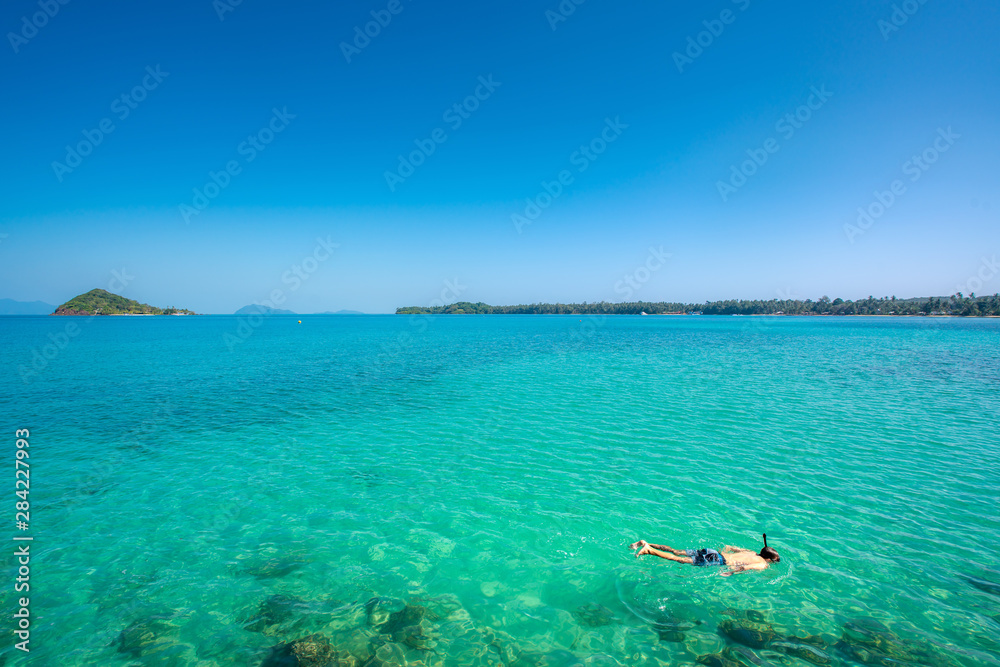 游客在泰国普吉岛热带度假胜地附近的水晶绿松石水中浮潜。夏天，瓦卡蒂