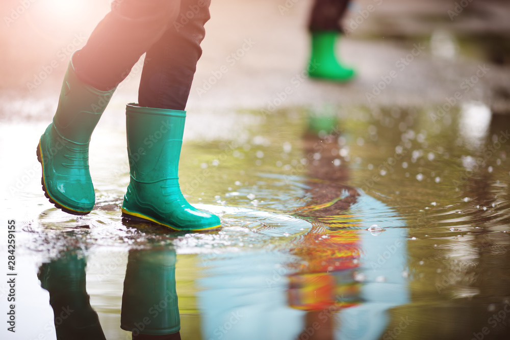 Child walking in wellies in puddle on rainy weather