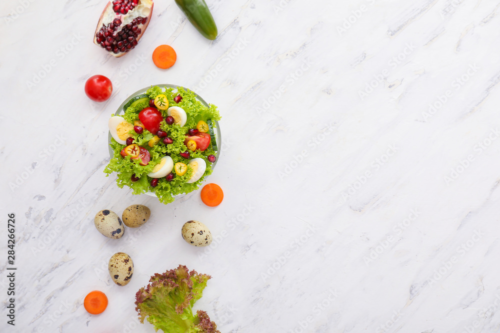 Bowl with quail eggs and vegetables on light background