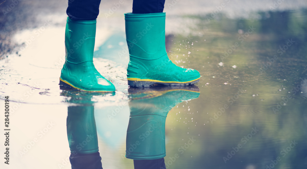 Child walking in wellies in puddle on rainy weather