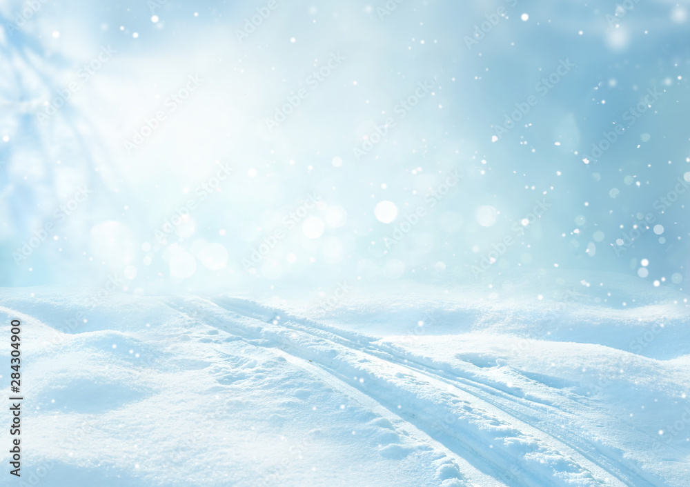 Winter snow blue background with snowdrifts, beautiful light, ski track and snow flakes on blue sky,