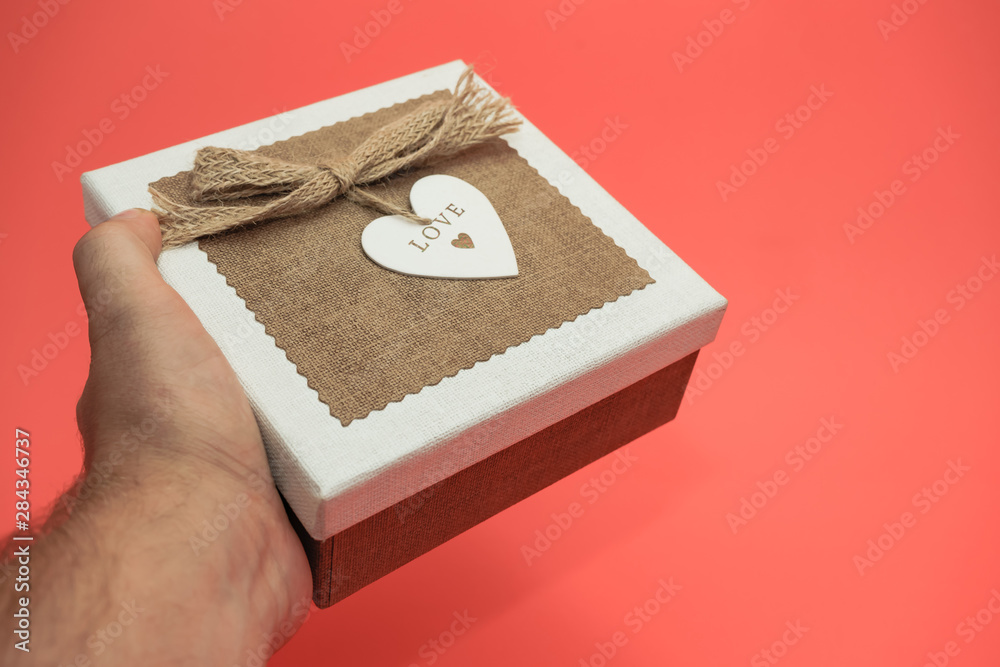 Hand holding Beautiful vintage gift box on a red background.