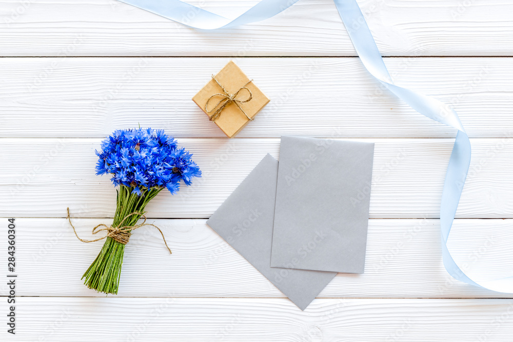 Summer flowers pattern with bouquet of blue cornflowers, envelopes and gift on white wooden backgrou