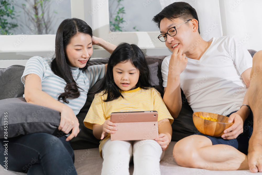 happiness asian family dad mom and daughter sit relax wachting tablet togehter home sweet home conce