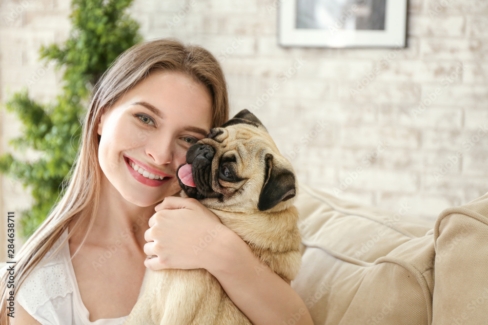 Beautiful young woman with cute pug dog at home