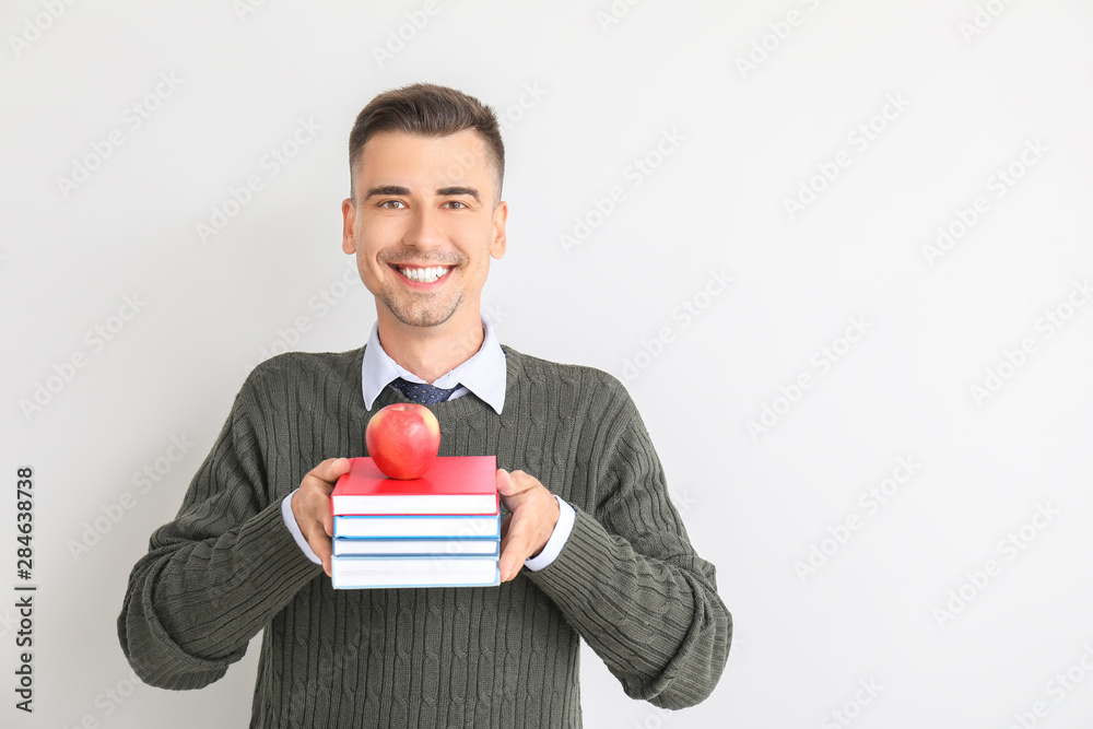 Handsome male teacher with books on white background