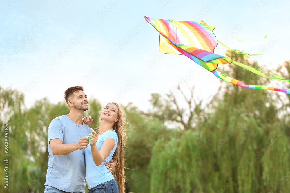 Happy young couple flying kite outdoors