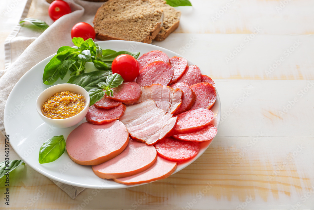 Plate with assortment of sausages, sauce and bread on light table