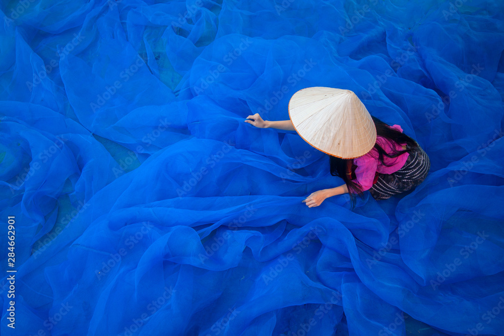 Beautiful woman fisherman is cleaning The fishing nets.