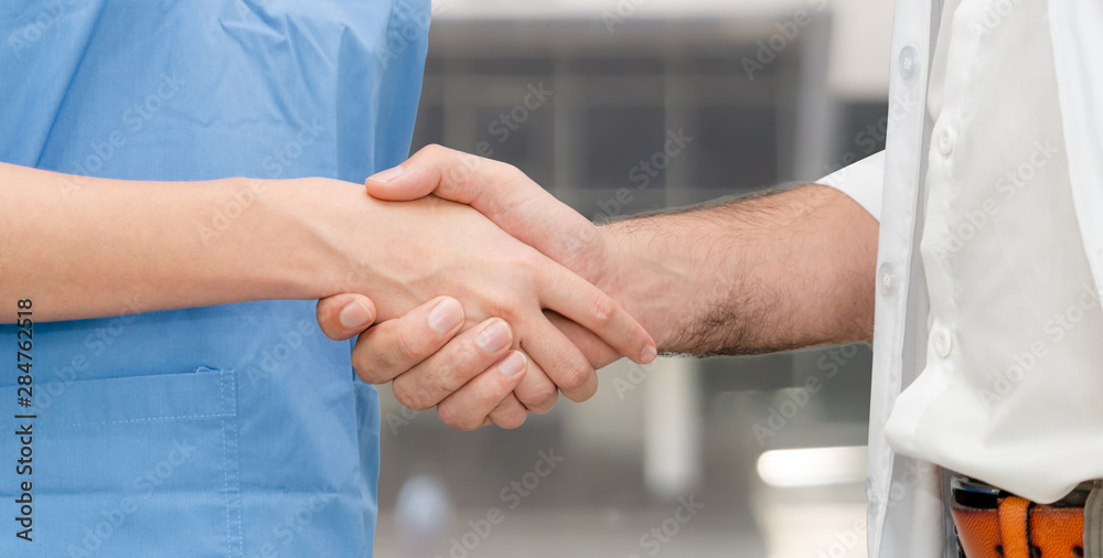 Doctor in hospital handshake with another doctor. Healthcare people teamwork and medical service con