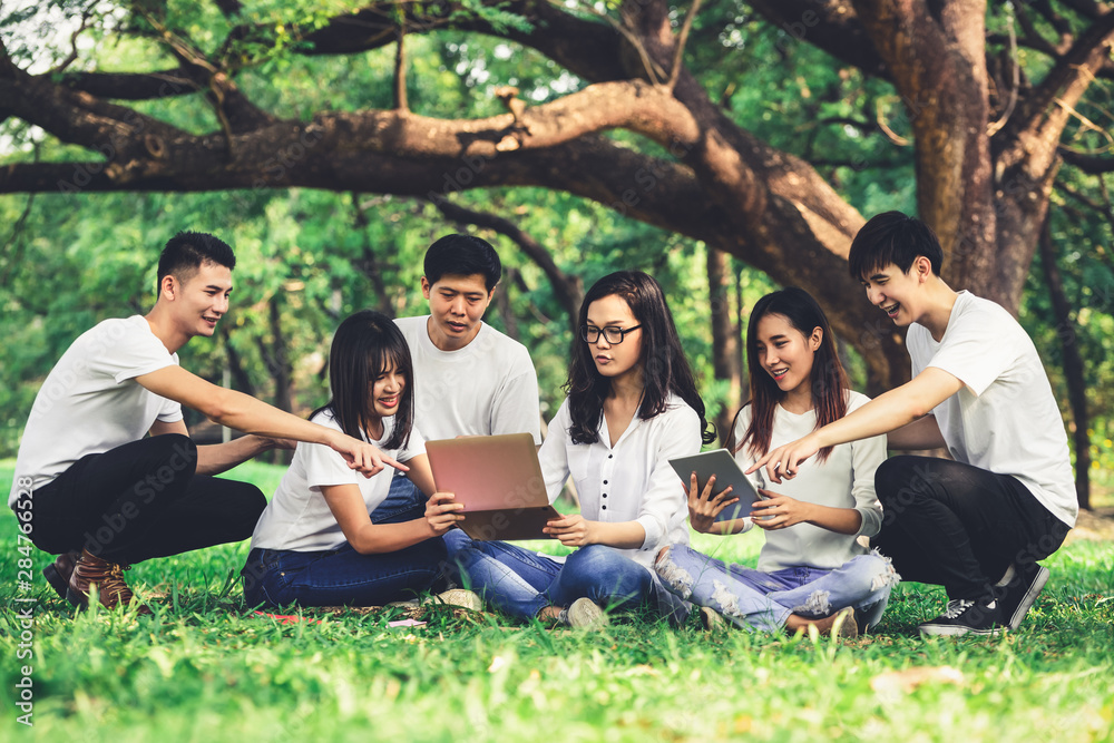 在大学或学校公园的小组项目中学习的年轻学生团队。学习快乐