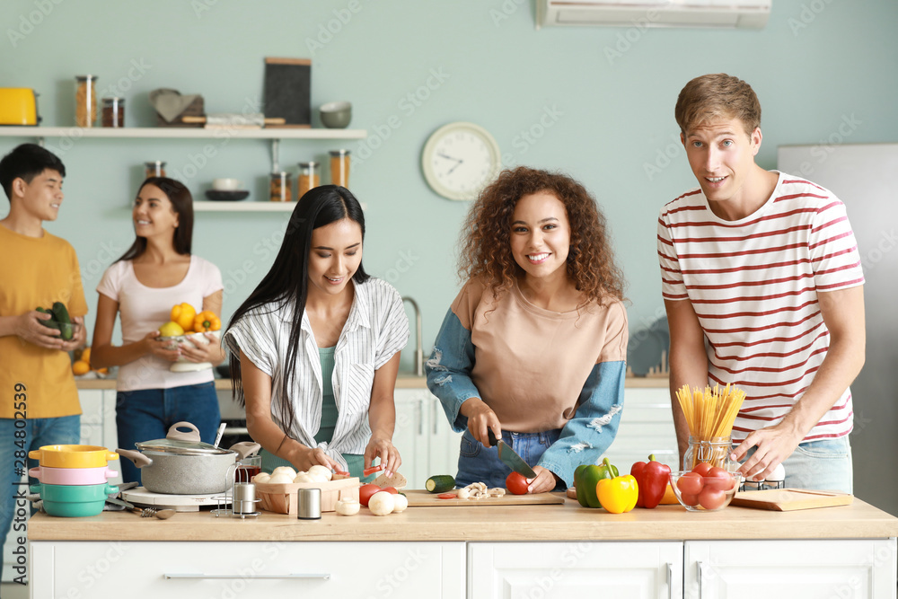 Happy friends cooking together in kitchen