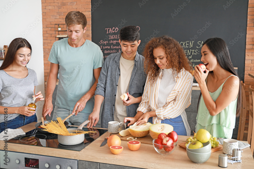 Happy friends cooking together in kitchen