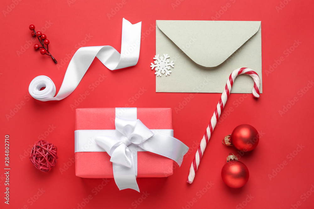 Christmas gift box with envelope and decor on color background