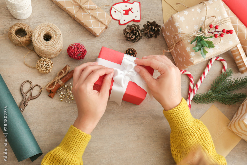 Woman making Christmas gift at wooden table