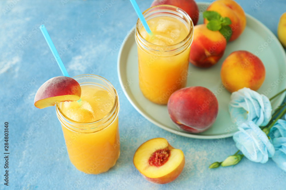 Jars of tasty peach juice on color background