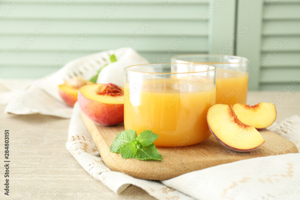 Glasses of tasty peach juice on wooden board