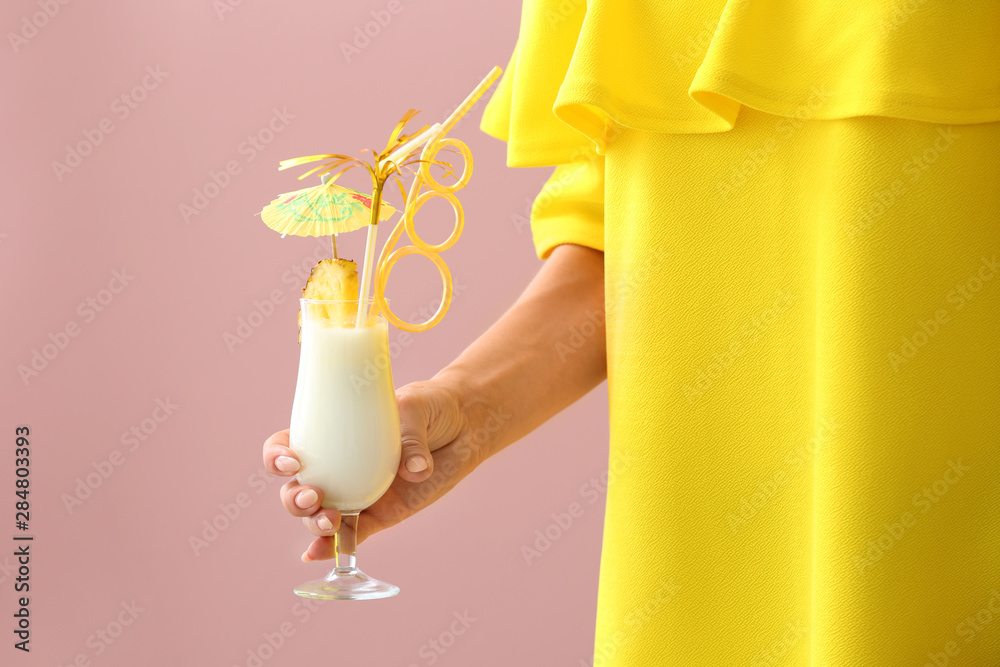 Woman with glass of tasty Pina Colada cocktail on color background