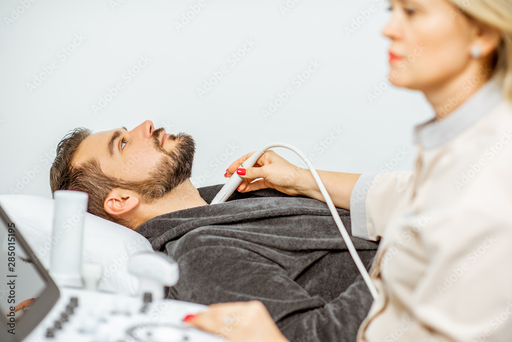 Doctor examining mens thyroid with ultrasound