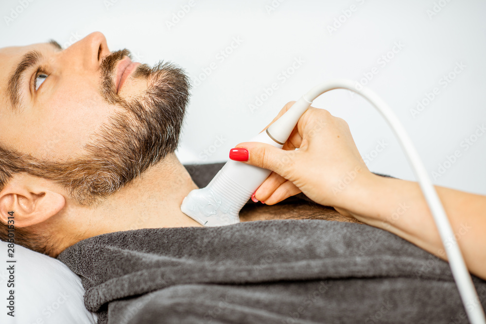 Men examining his thyroid with ultrasound