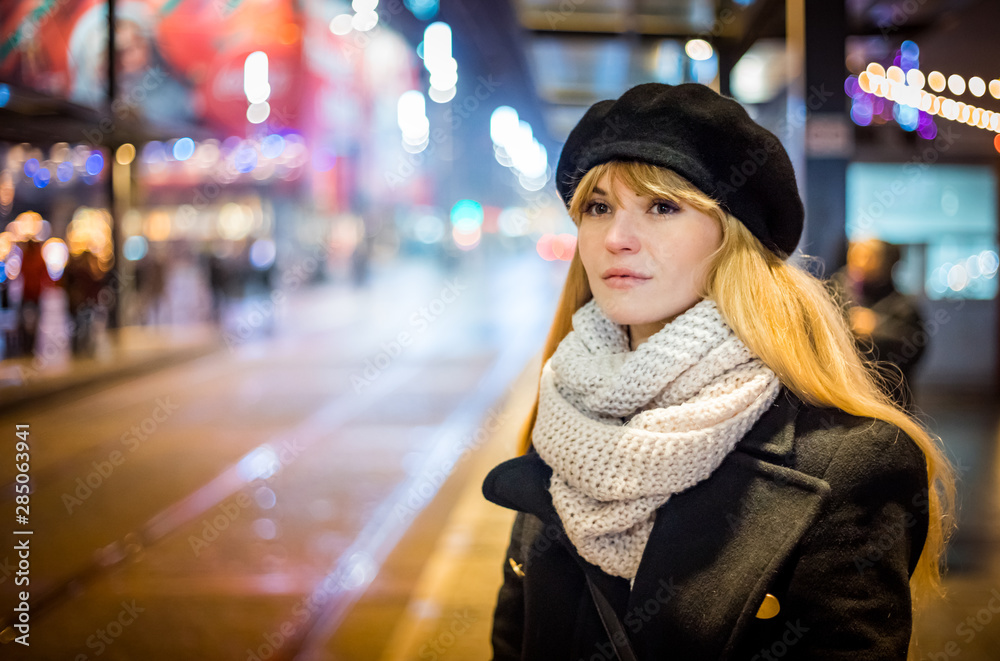 Young woman in the night city waiting at bus stop