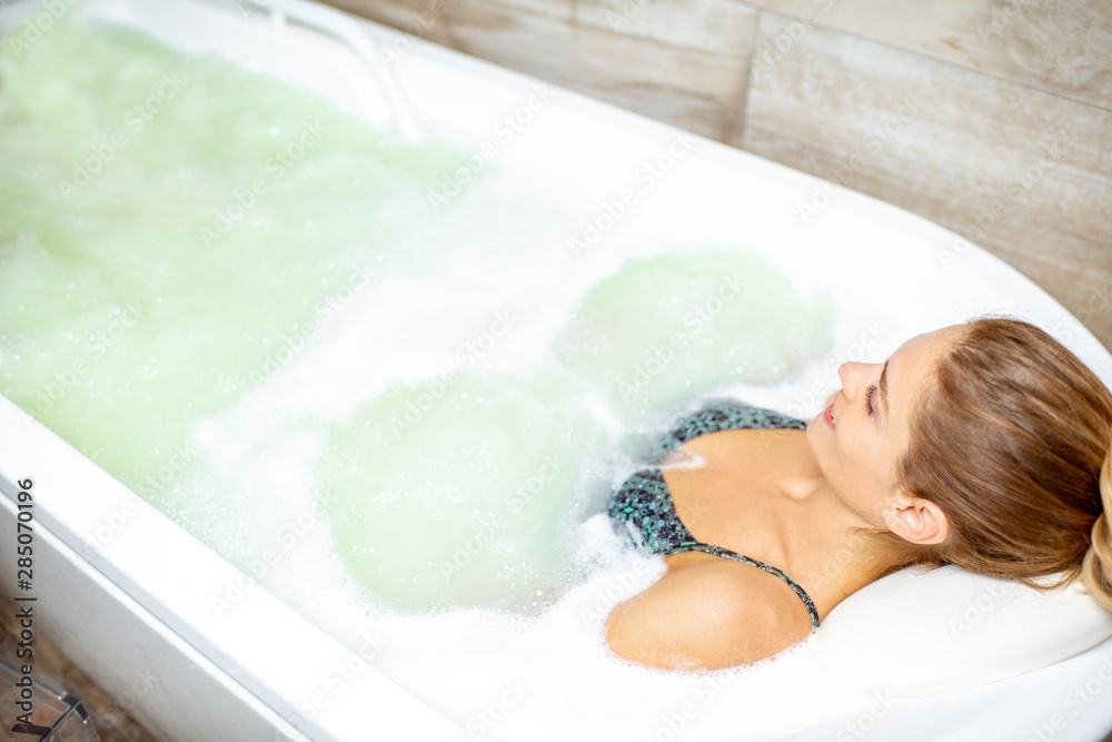 Beautiful woman relaxing in the bathtub having a hydromassage therapy in the SPA