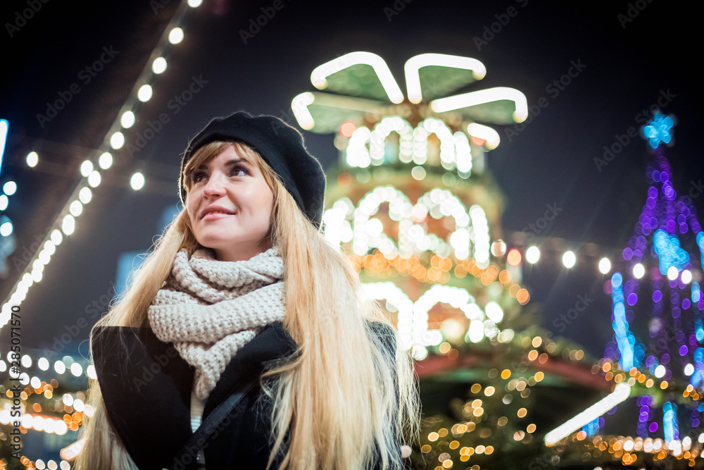 Happy smiling girl at Christmas market, illuminated bokeh background