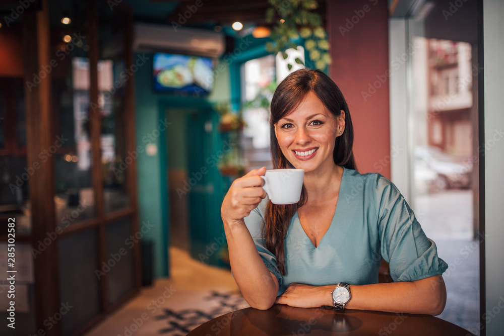 Portrait of a brunette woman enjoying cup of coffee at restaurant