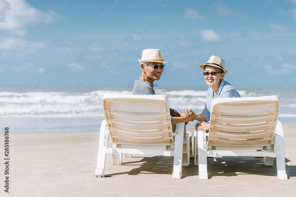 亚洲老年夫妇或老年人周末度假时在海滩散步和坐着