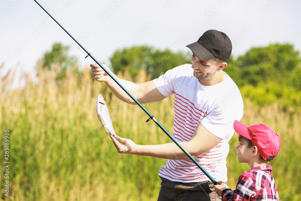 Father and son fishing together on river