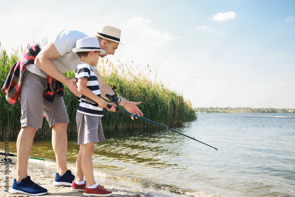 Father and son fishing together on river