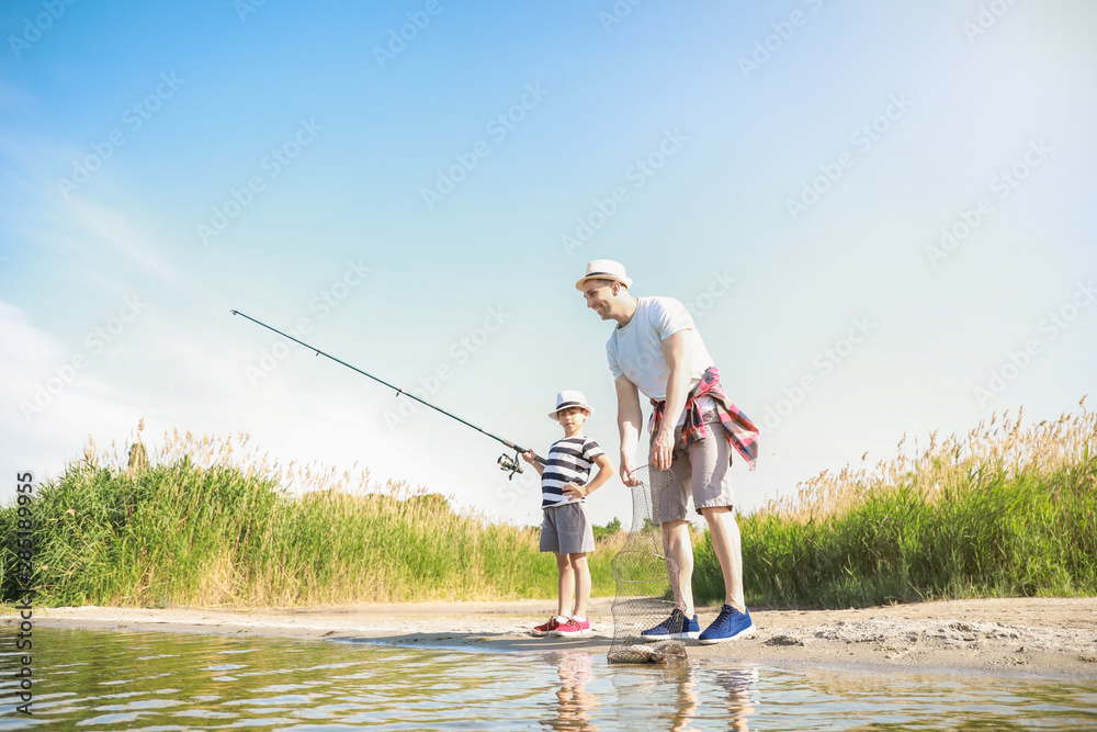 Father and son fishing together on river